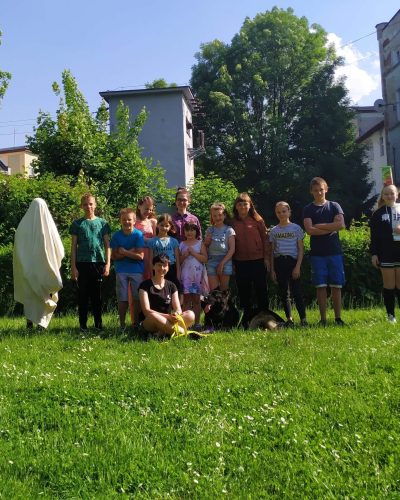 Trenerka psów z owczarkiem staroniemieckim podczas spotkania z dziećmi.