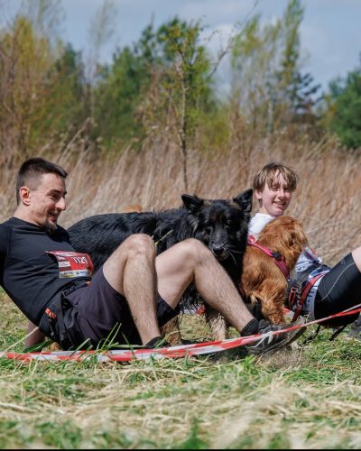 Ujęcie w ruchu z biegu Hard Dog Race - psy przyglądają się swoim opiekunom poruszającym się w nietypowej formie - na czworaka.