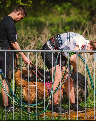 Uczestnicy Hard Dog Race po biegu zmywają błoto z siebie oraz ze swoich psów.